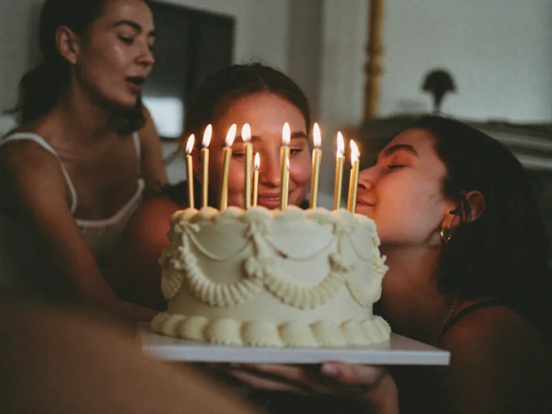 Candlelight from a birthday cake lighting the faces gathered around it.