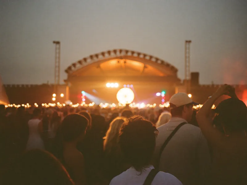 Friends dancing in front of a warm stage glow at an evening festival.