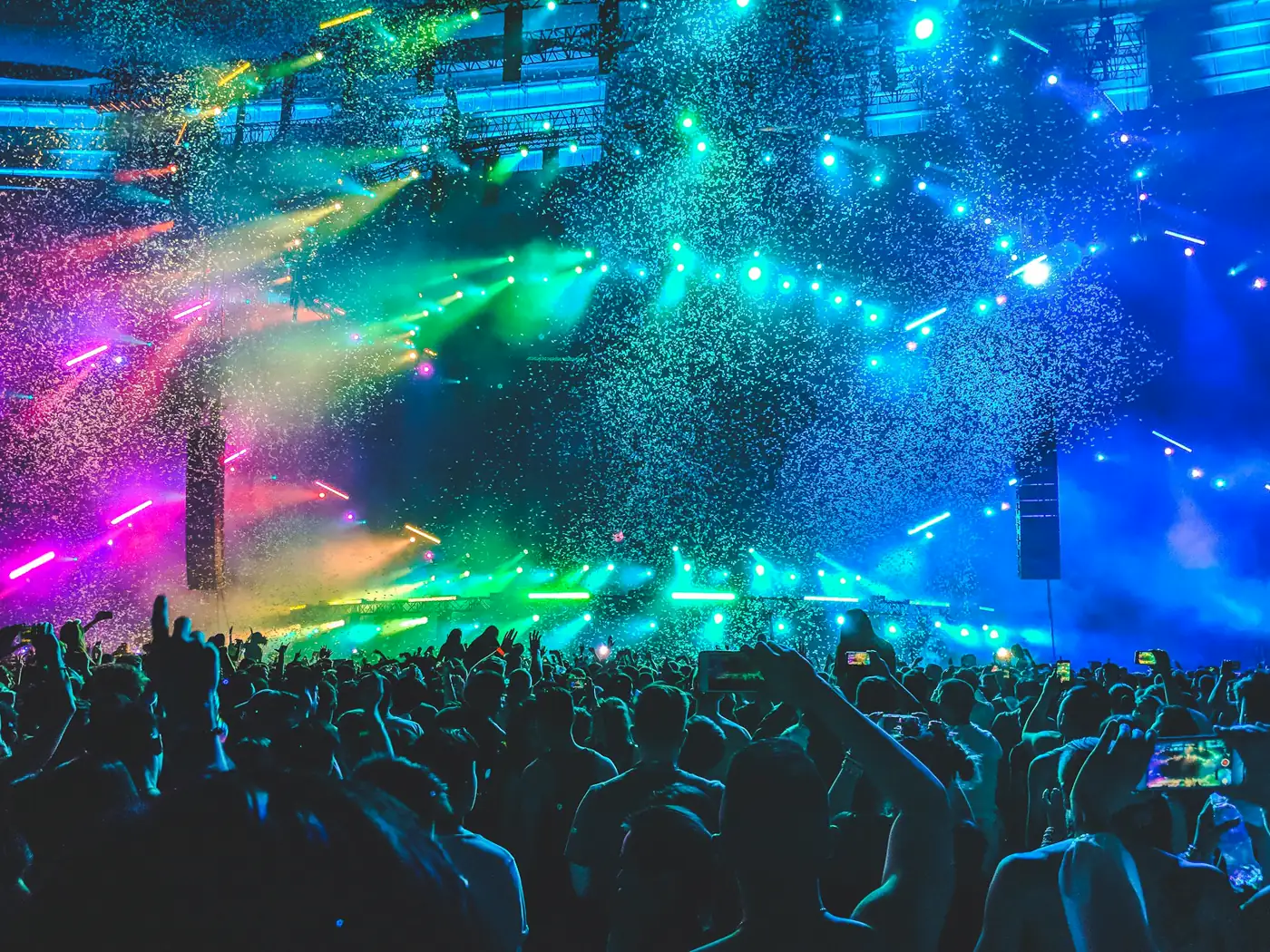 A crowd gathered in front of a lit stage at an outdoor festival.
