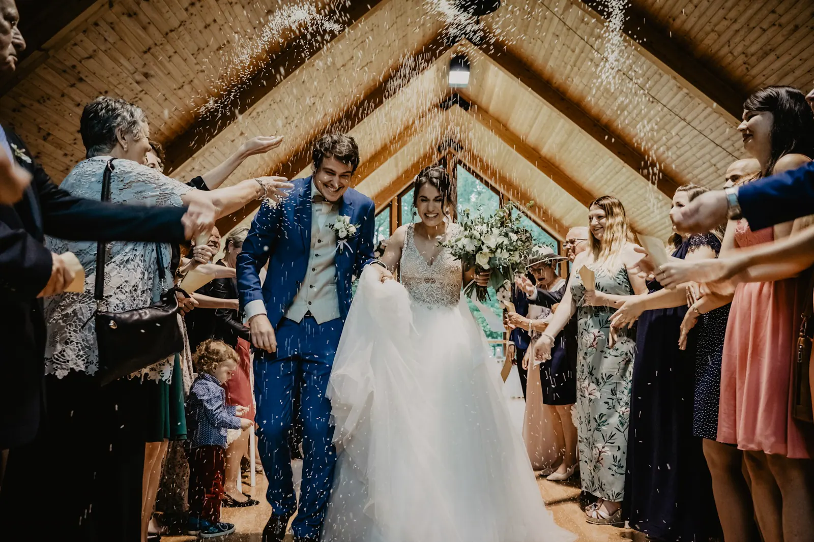 A bride and groom standing close together against a weathered wooden wall.